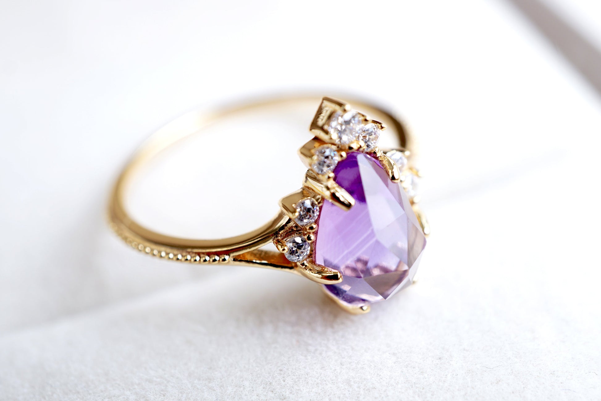 Gold ring with a purple gemstone on a white background