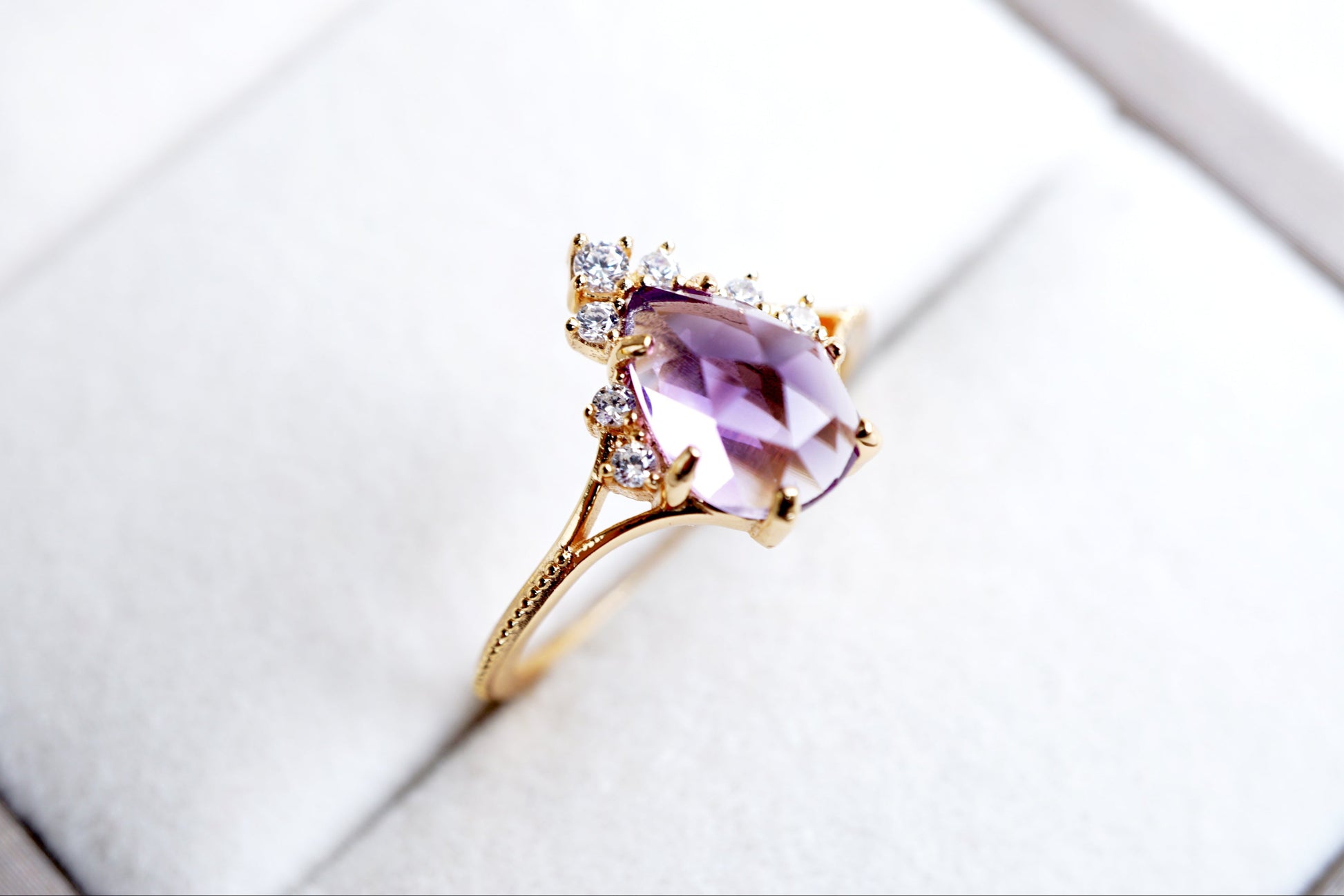 Gold ring with a purple gemstone on a white surface