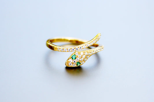 Gold ring with green gemstone on a light gray background