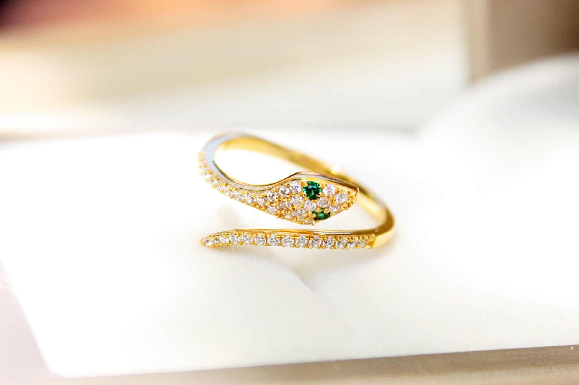 Gold ring with a green gemstone on a white surface