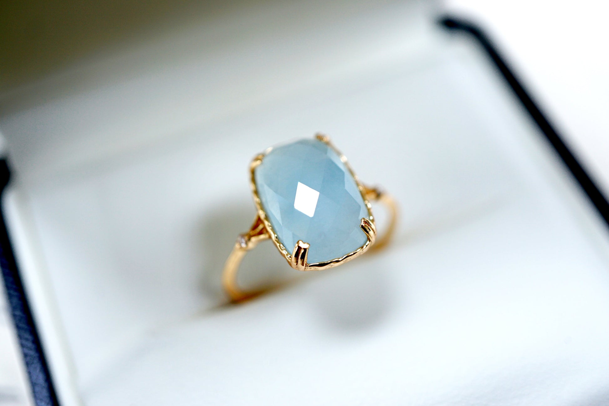 Gold ring with a light blue gemstone on a white background