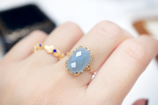 Gold ring with a blue gemstone on a hand