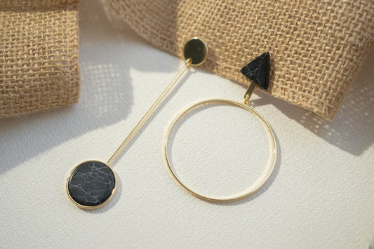 Gold hoop earrings with black stones on a light surface