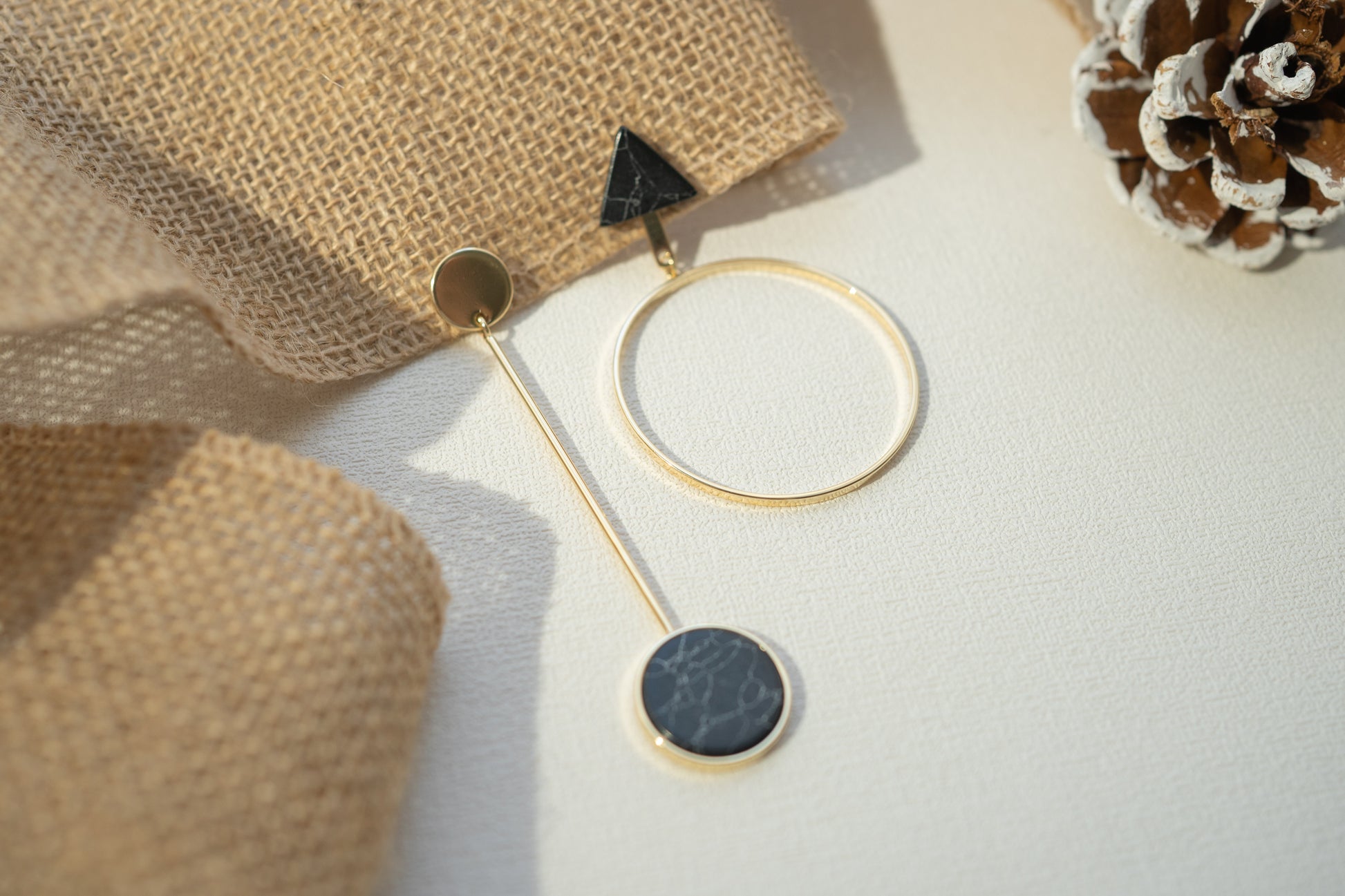 Gold earring with black stone on a textured surface
