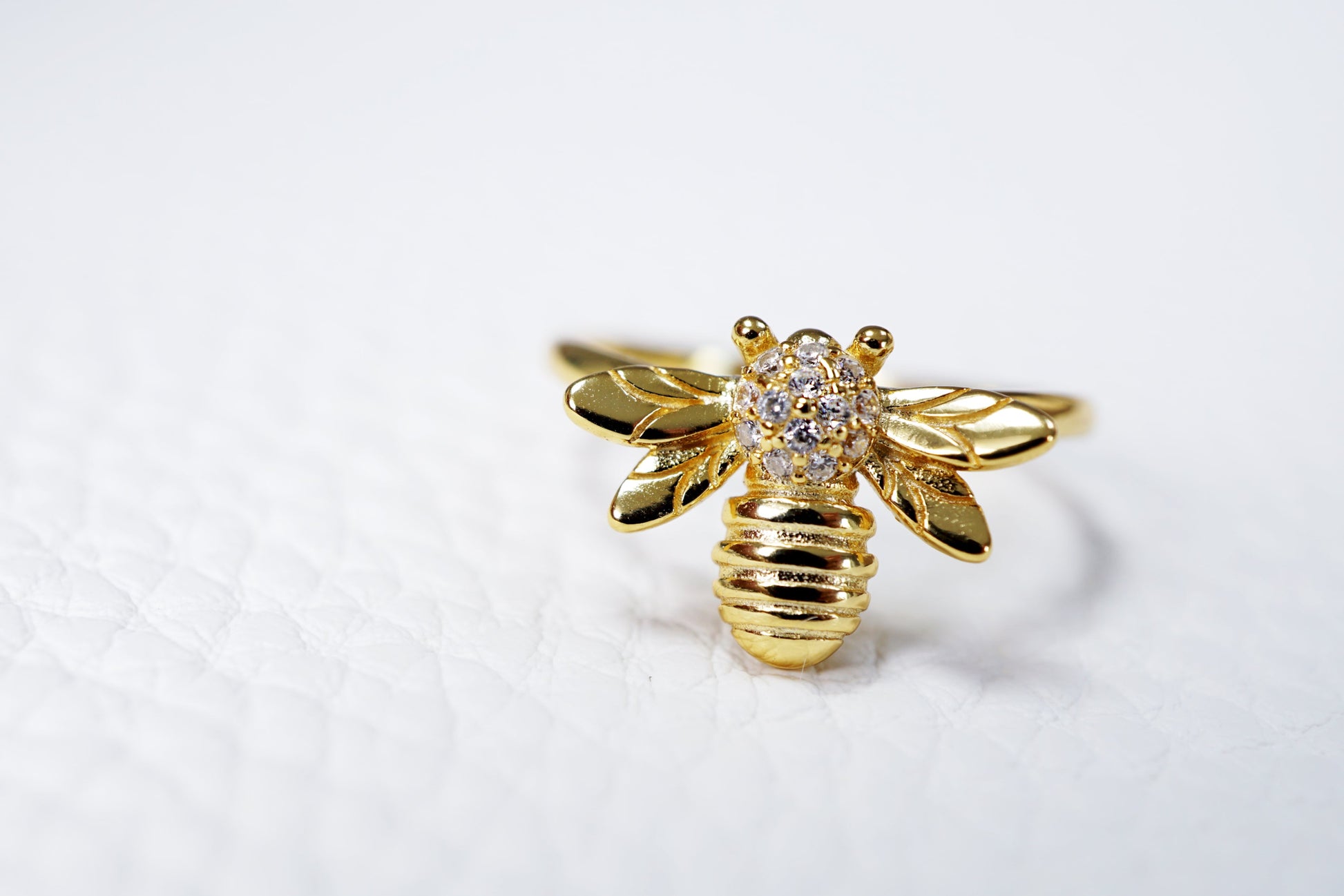 Gold bee-shaped ring with a diamond on a white background