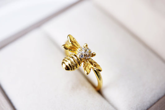 Gold bee-shaped ring with a diamond on a soft white background