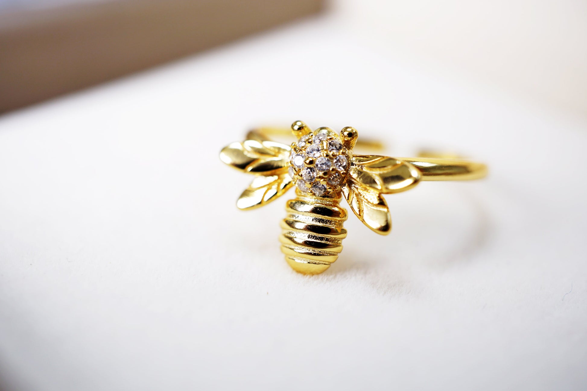 Gold bee-shaped ring with a diamond on a white cushion