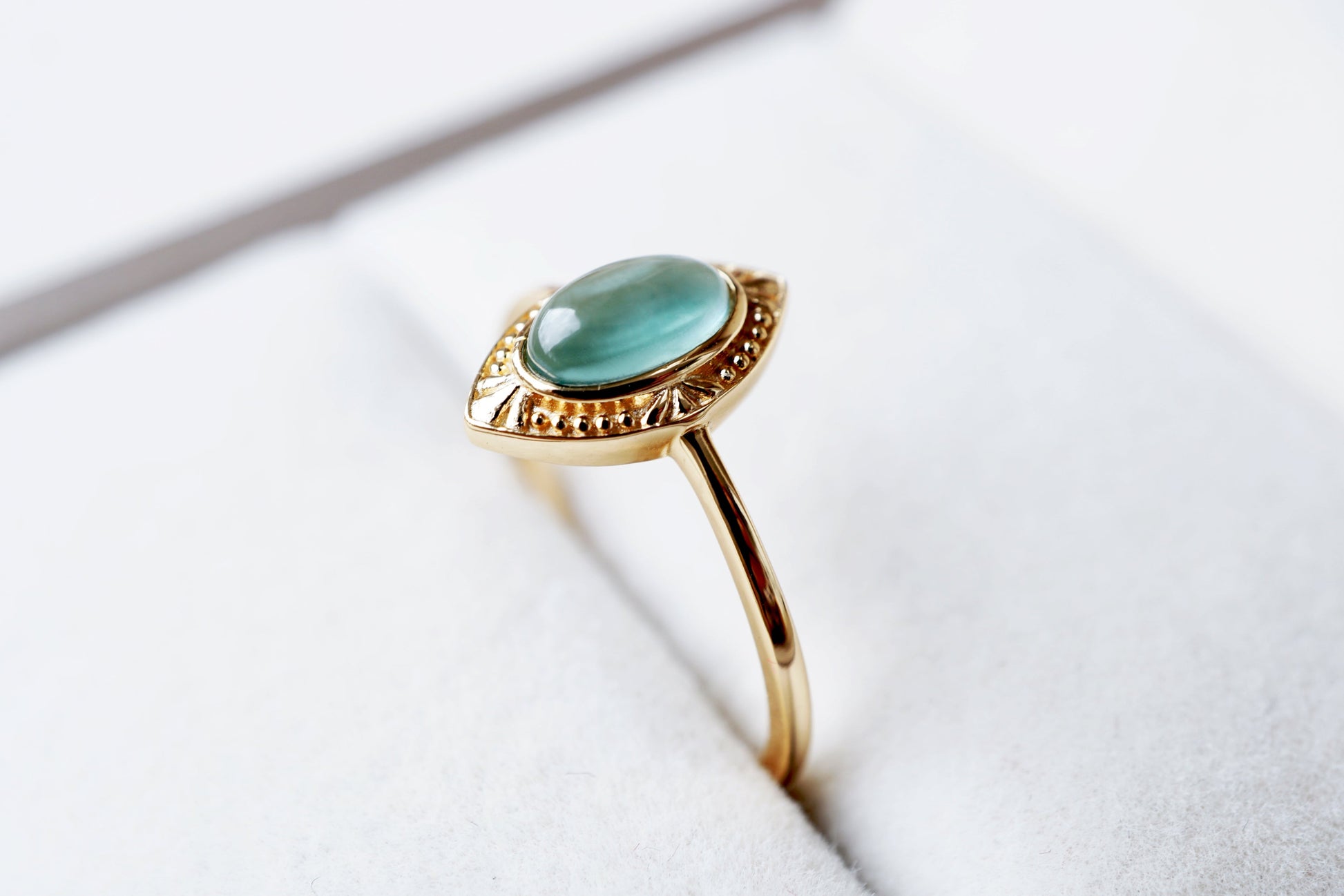 Gold ring with a green gemstone on a white surface