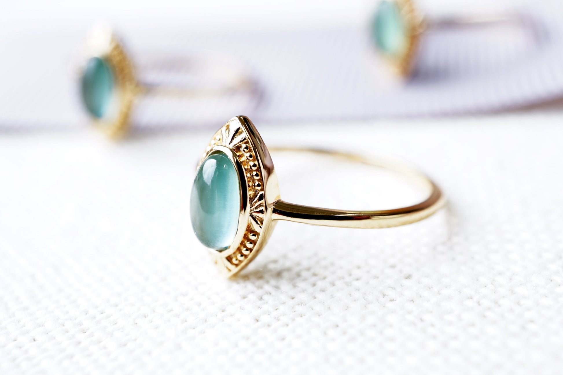 Gold ring with a green gemstone on a white background