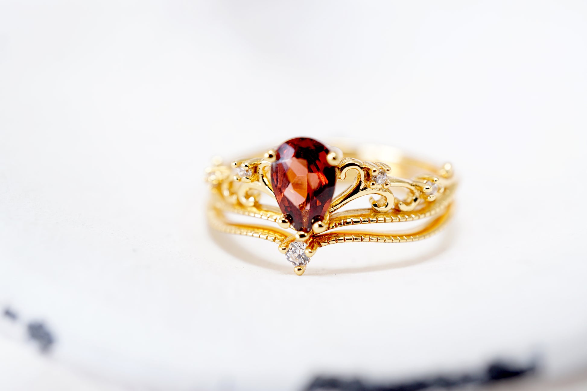 Gold ring with a heart-shaped gemstone on a marble surface