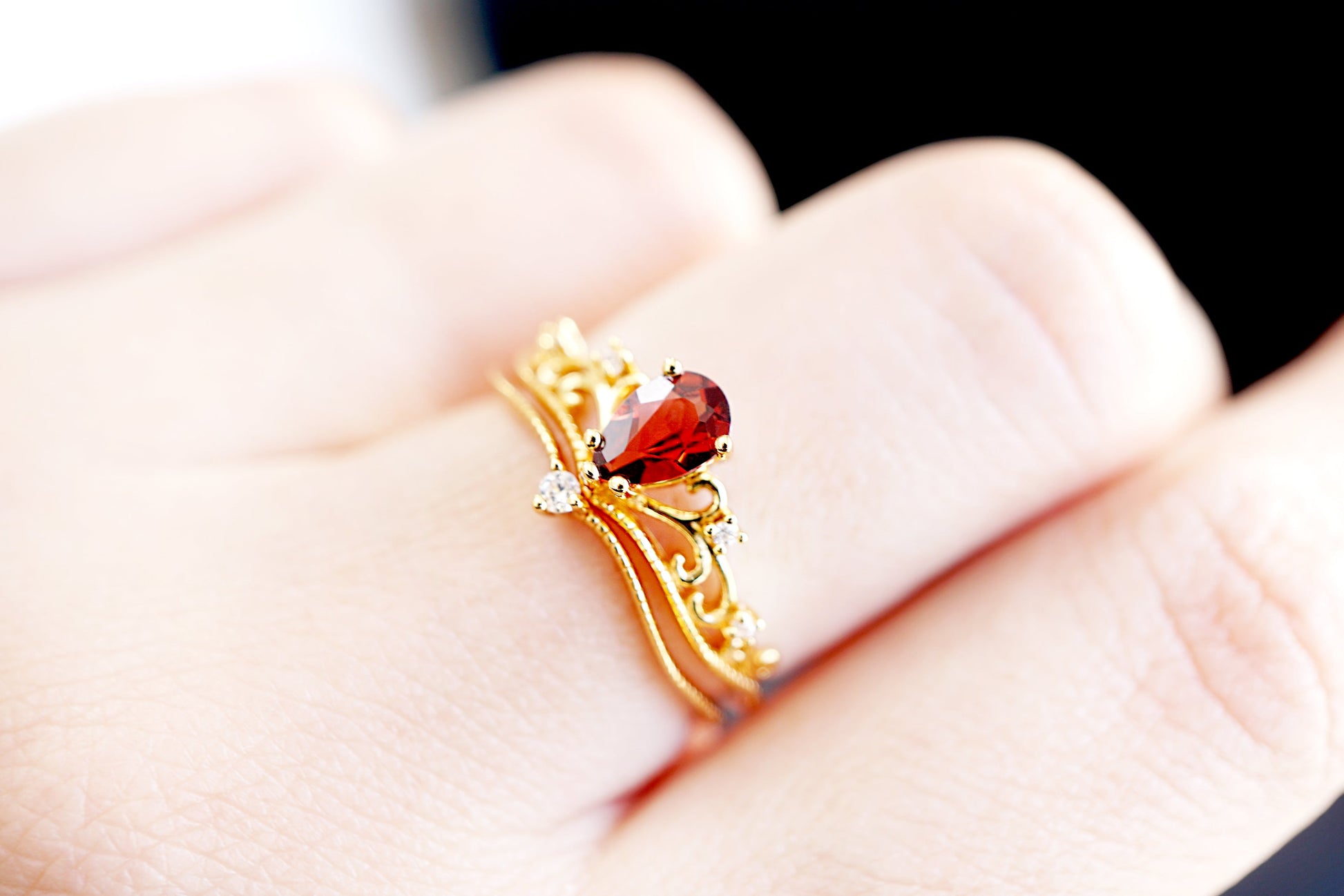 Gold ring with a red gemstone on a hand against a blurred background