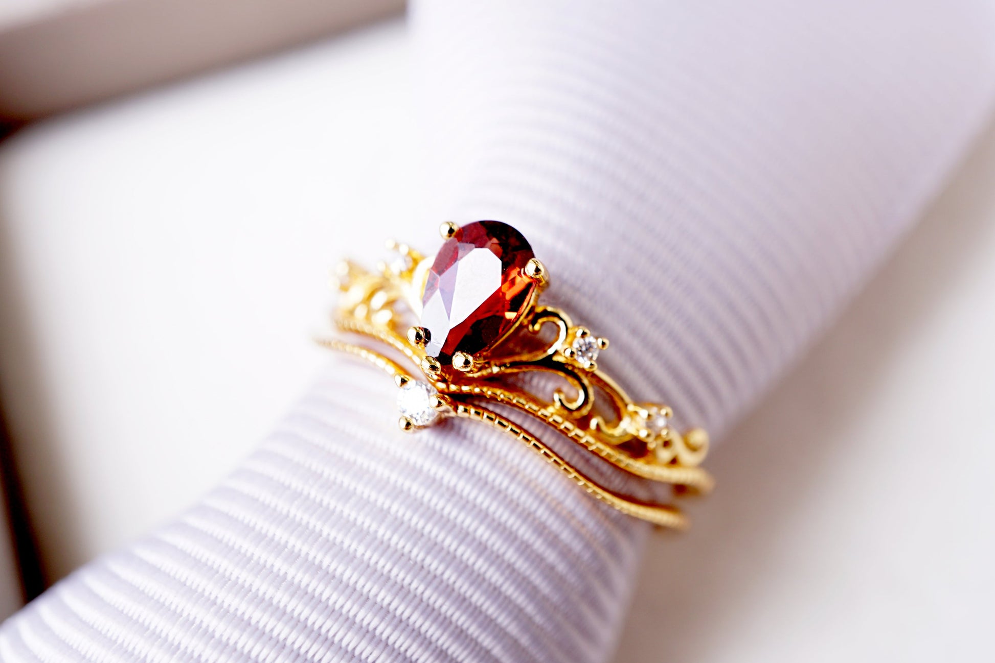Gold ring with a red gemstone on a white surface