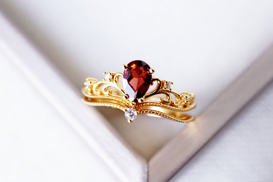 Gold brooch with a red gemstone on a white background