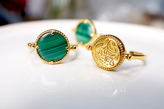 Gold ring with green stone on a white surface