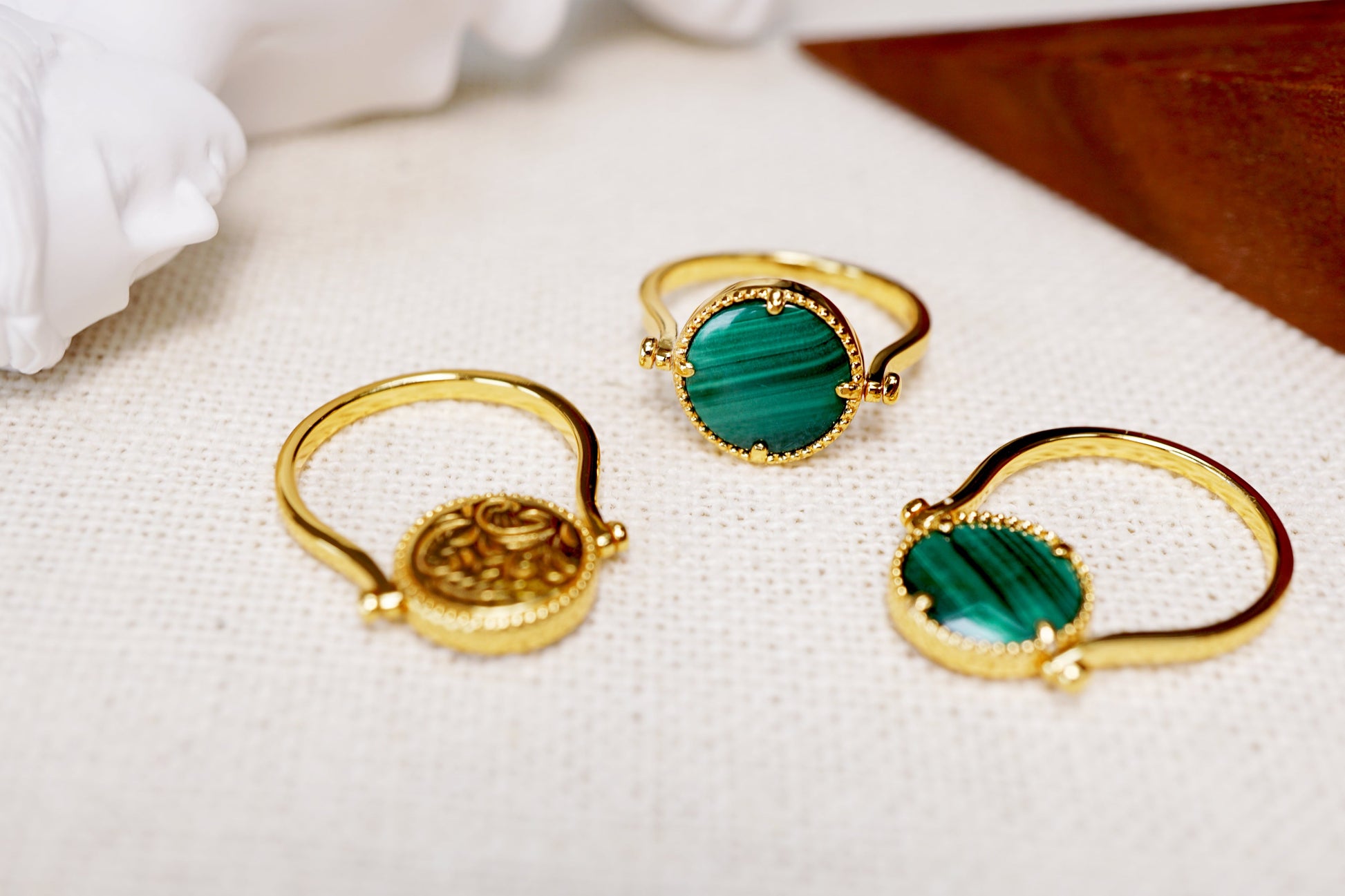 Gold rings with green gemstones on a white surface