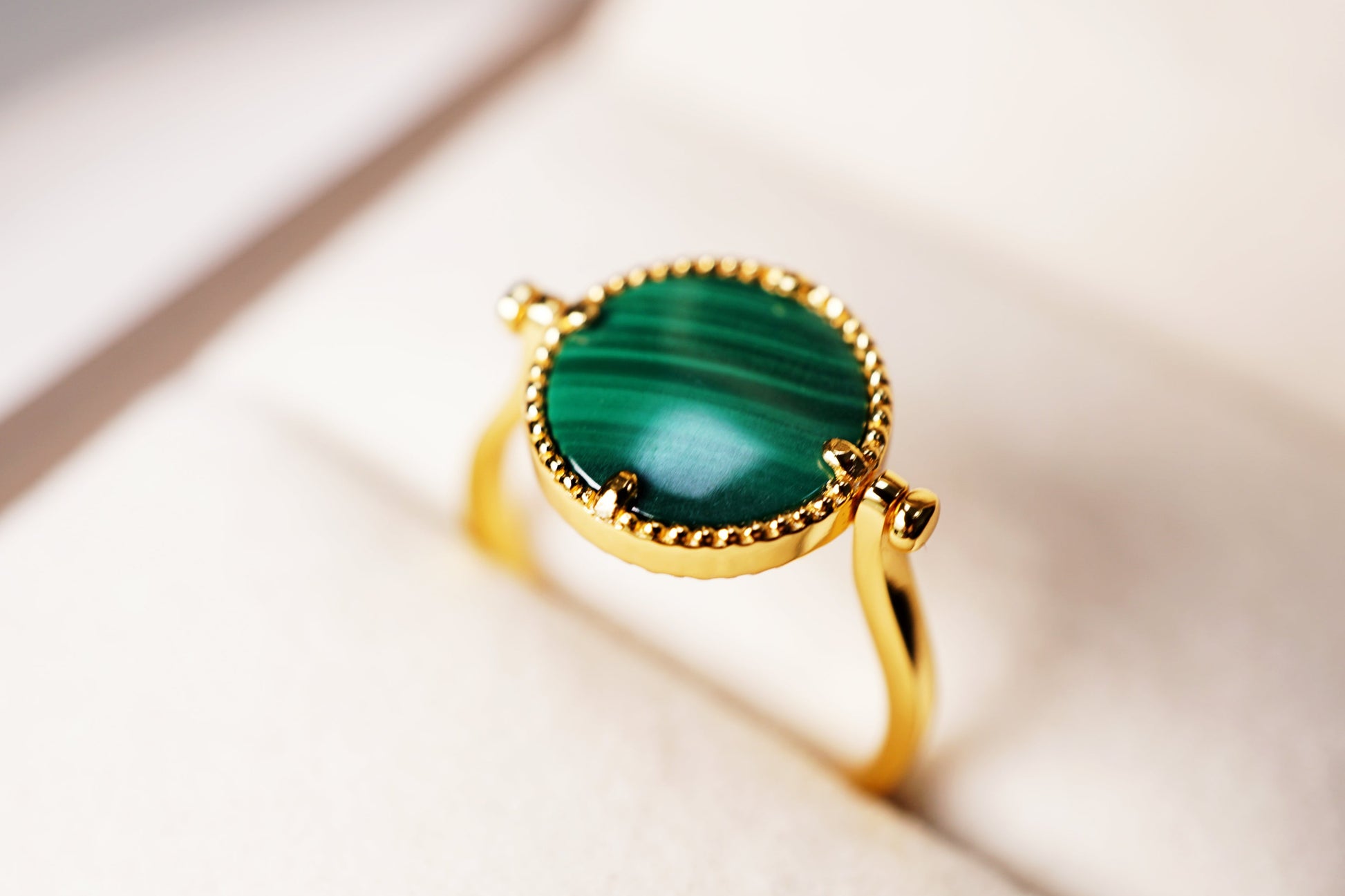 Gold ring with a green gemstone on a light background