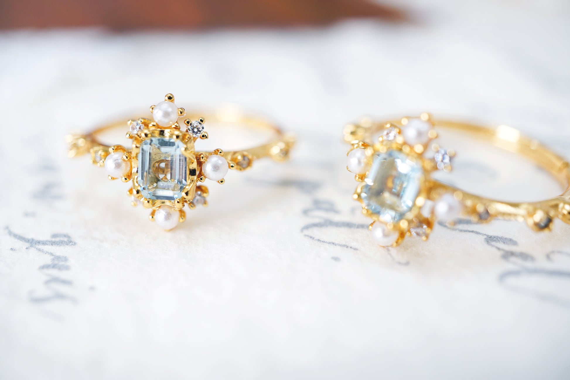 Two gold rings with gemstones on a textured surface