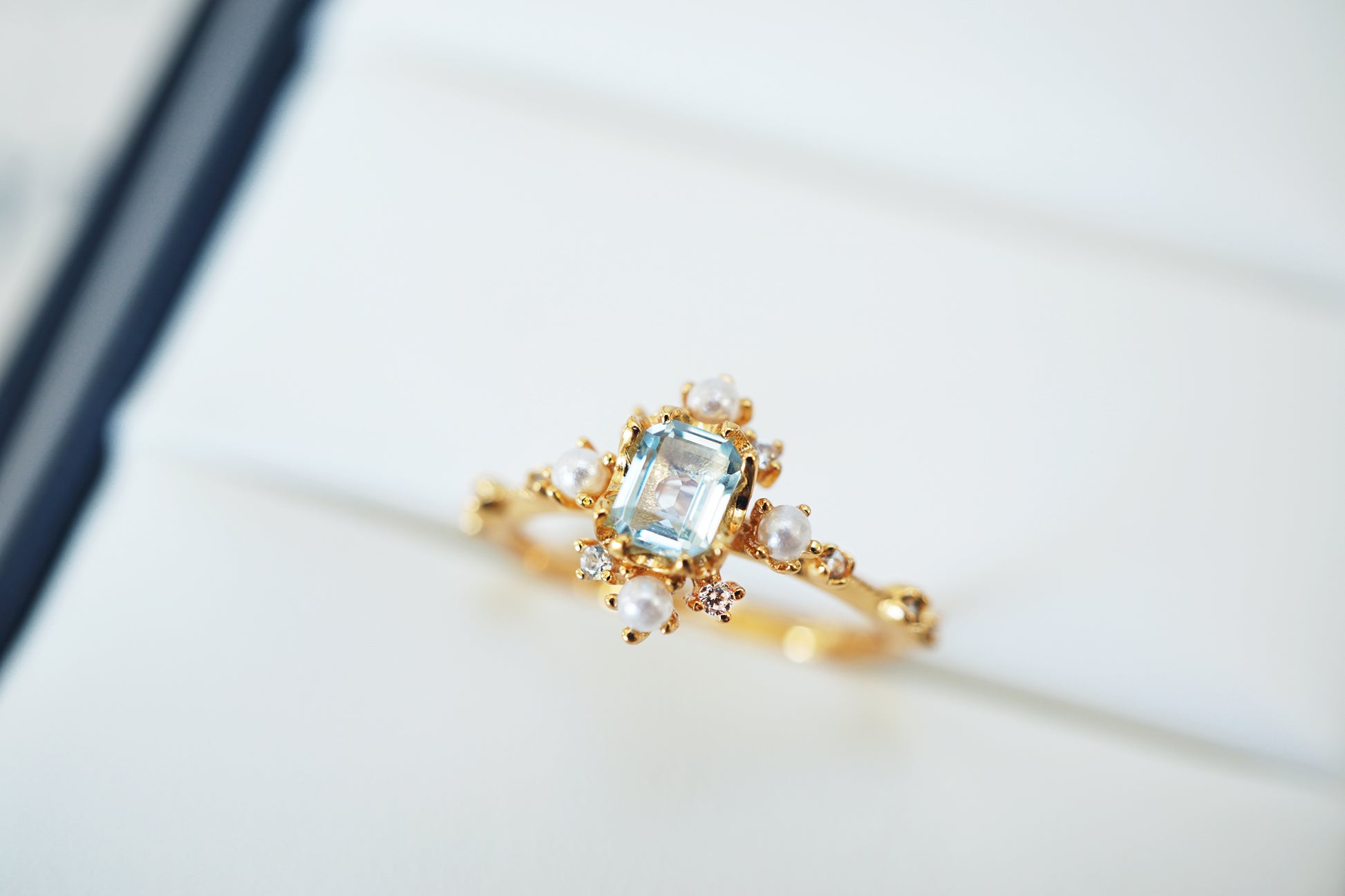 Gold ring with a blue gemstone on a white background
