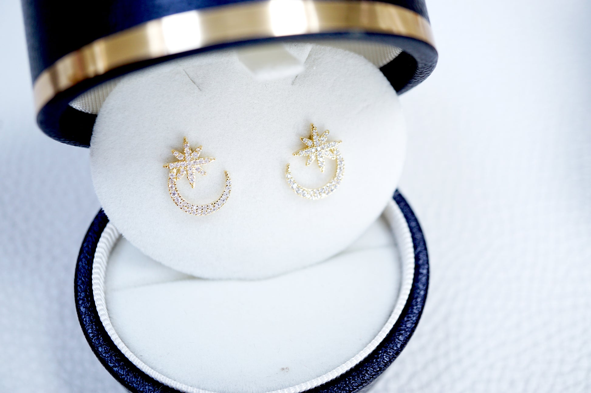 Gold earrings in a jewelry box on a white background