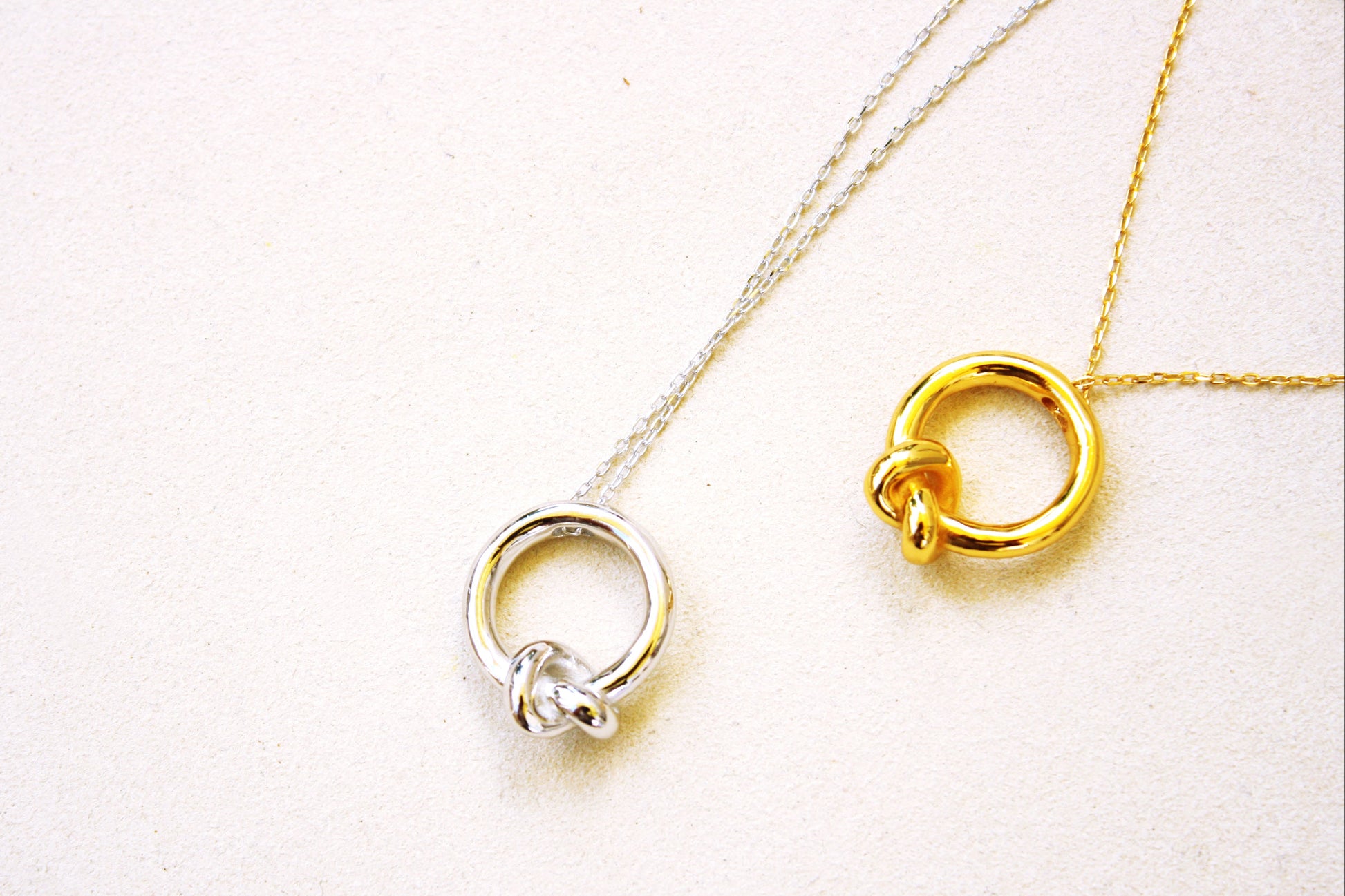 Two gold necklaces with interlocking rings on a white background