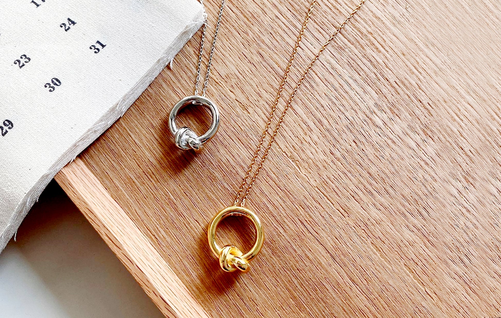 Two necklaces with circular pendants on a wooden surface
