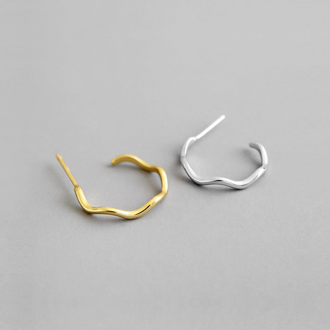 Gold and silver hoop earrings on a gray background
