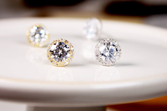 Diamond stud earrings on a white plate with a blurred background