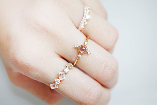 Close-up of a hand wearing multiple rings with gemstones on a light background