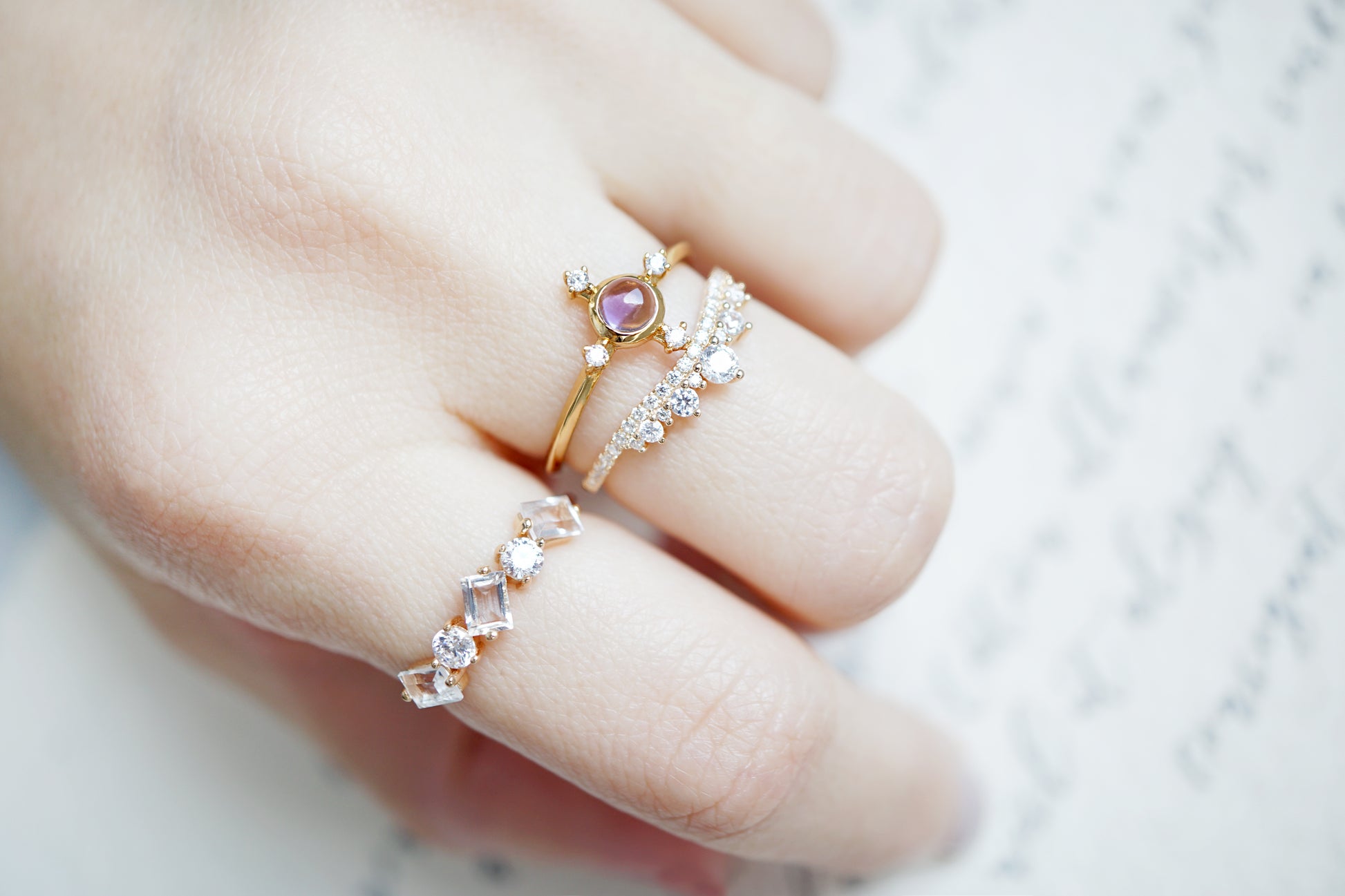 Close-up of a hand wearing two decorative rings with gemstones on a soft background