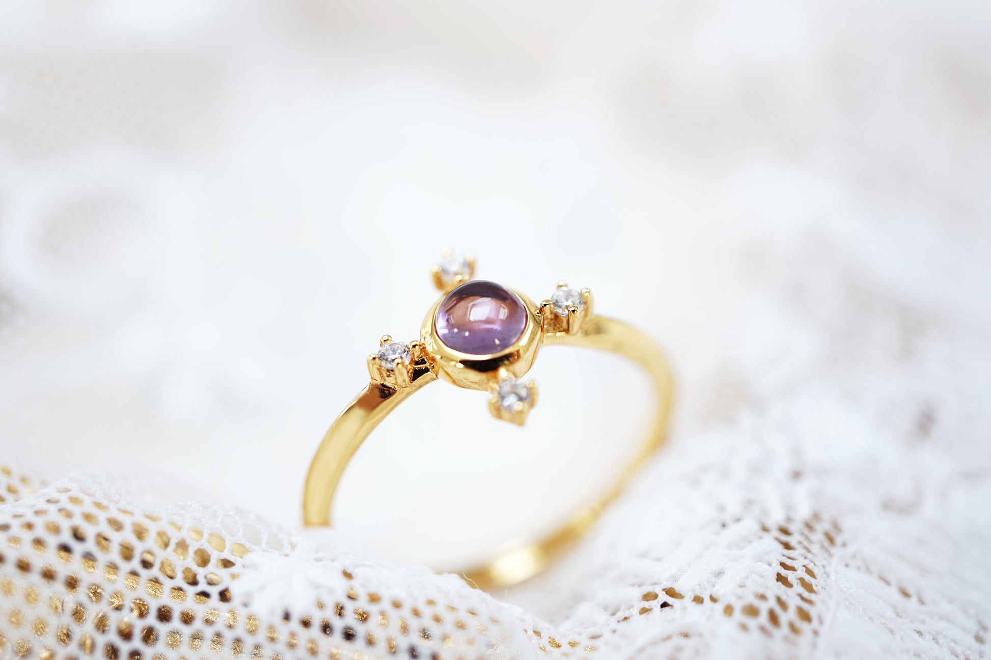 Gold ring with a purple gemstone on a textured white surface