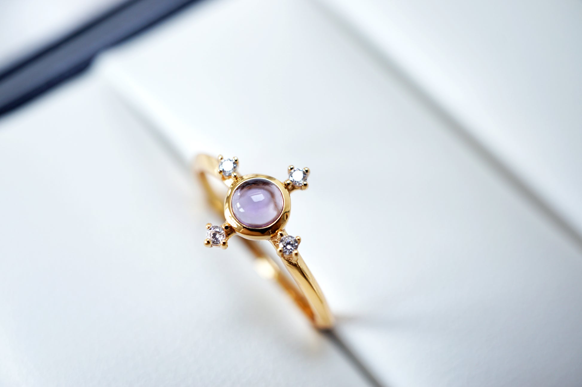 Gold ring with a pink gemstone and small diamonds on a light background