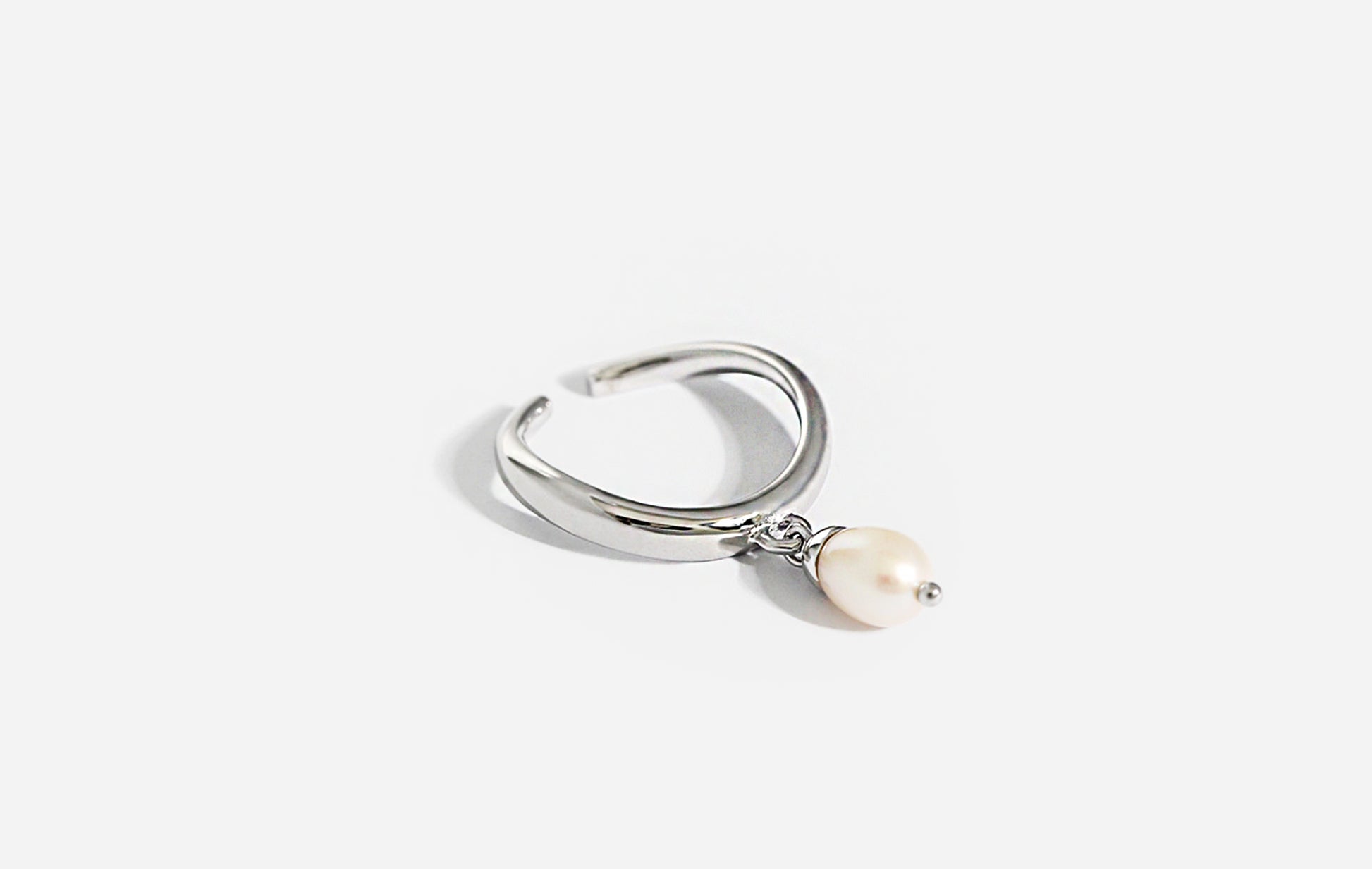 Silver ring with a pearl charm on a white background