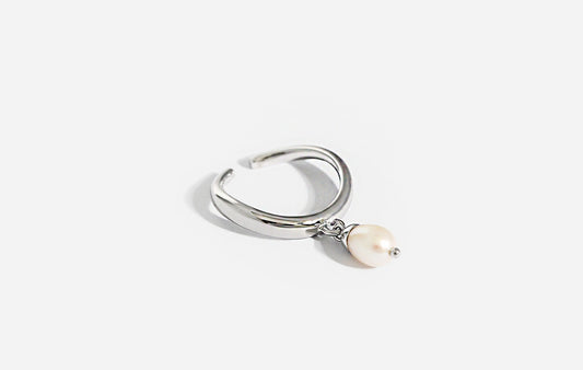 Silver ring with a pearl charm on a white background