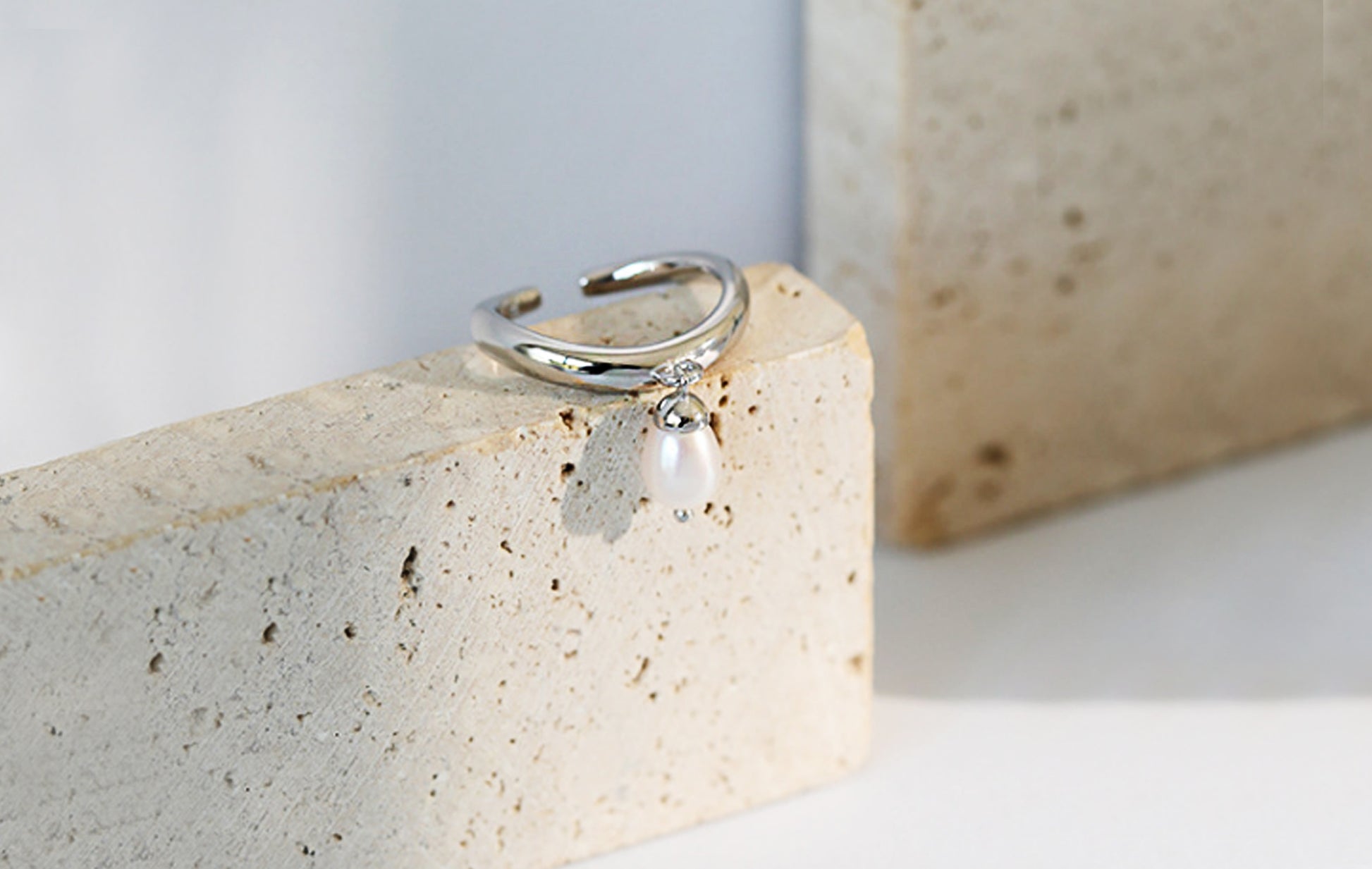 Silver ring with a pearl on a textured stone surface