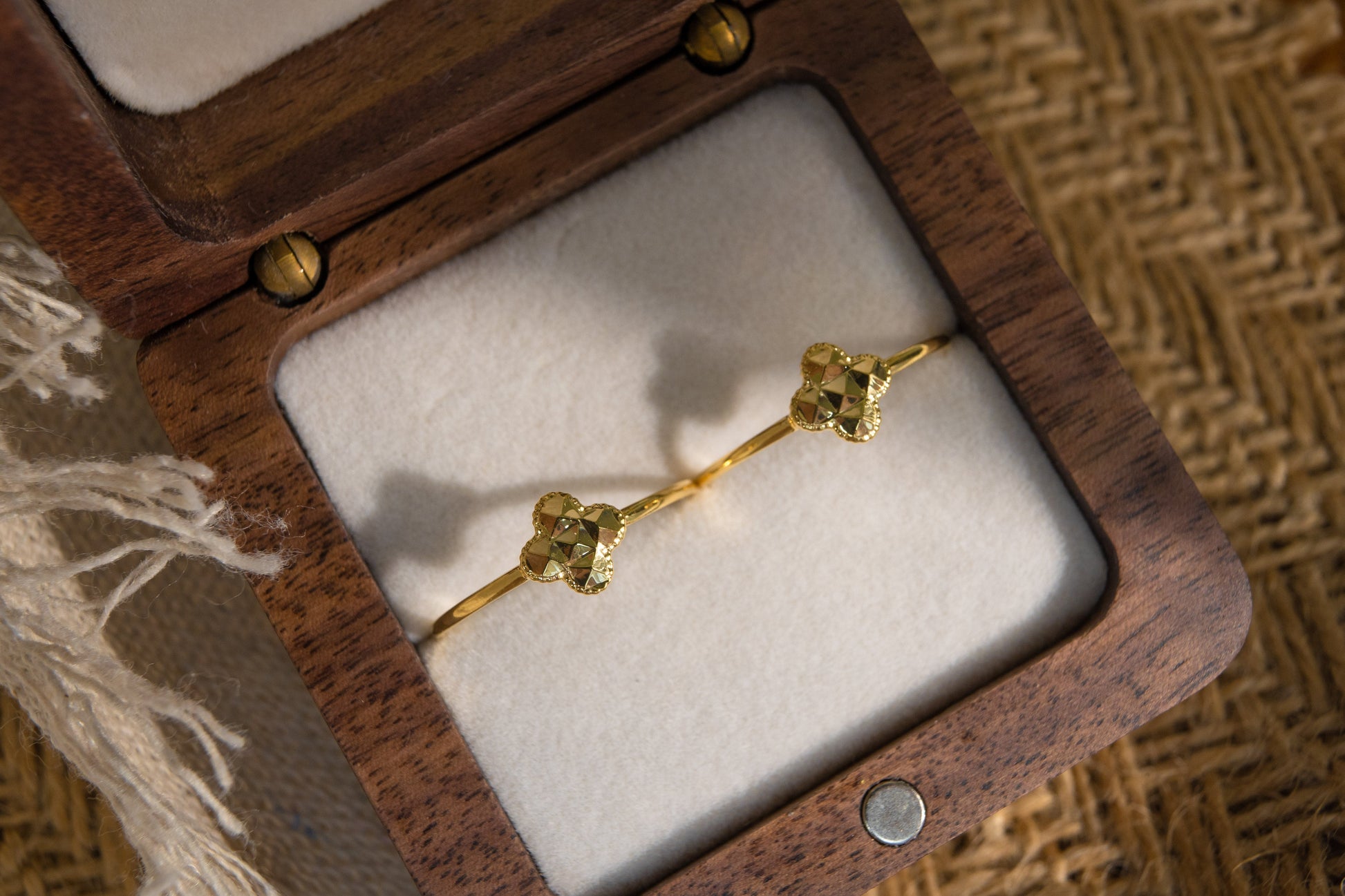Gold bracelet in a wooden jewelry box on a textured surface
