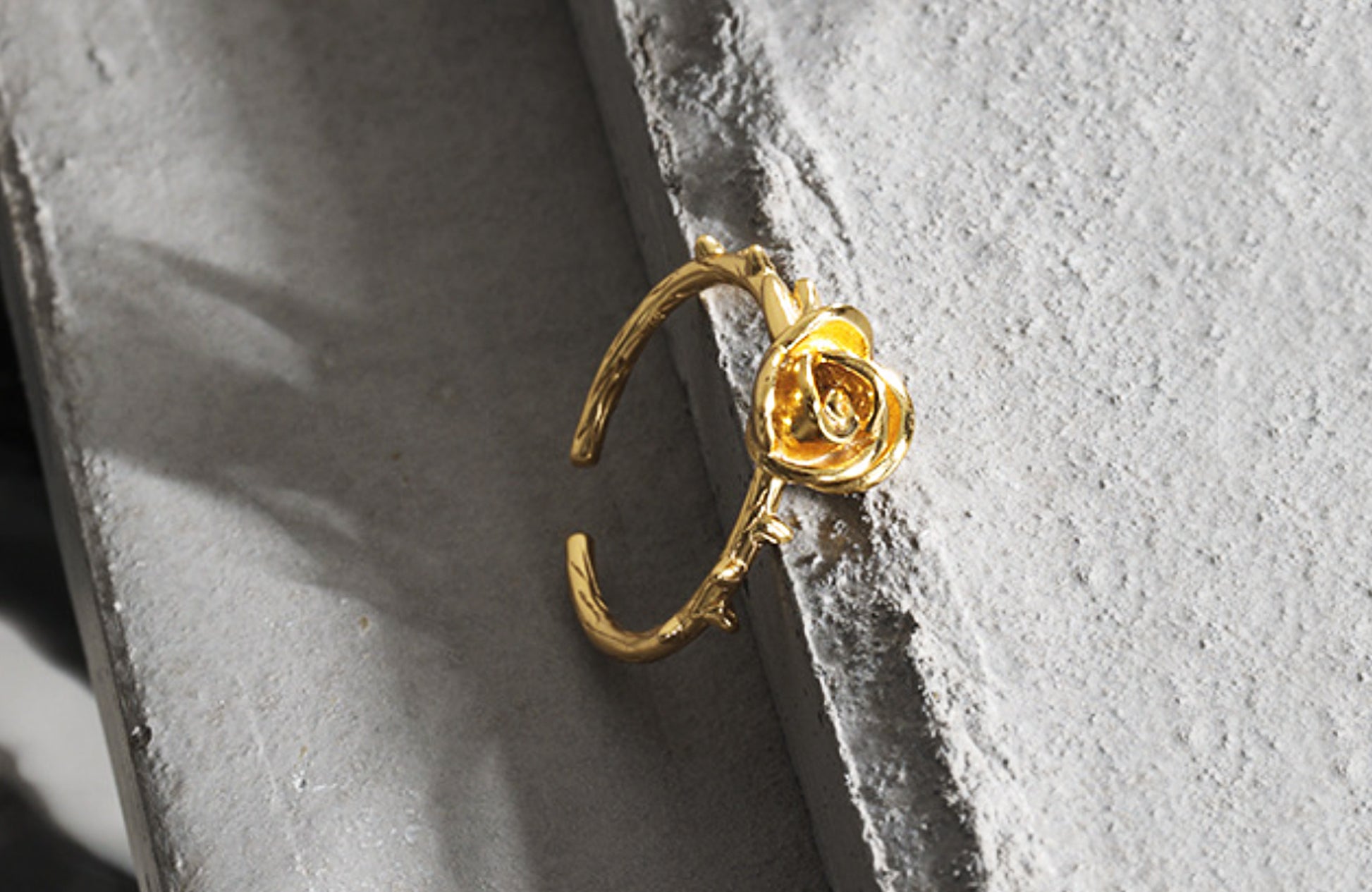 Gold ring with a rose design on a textured gray surface