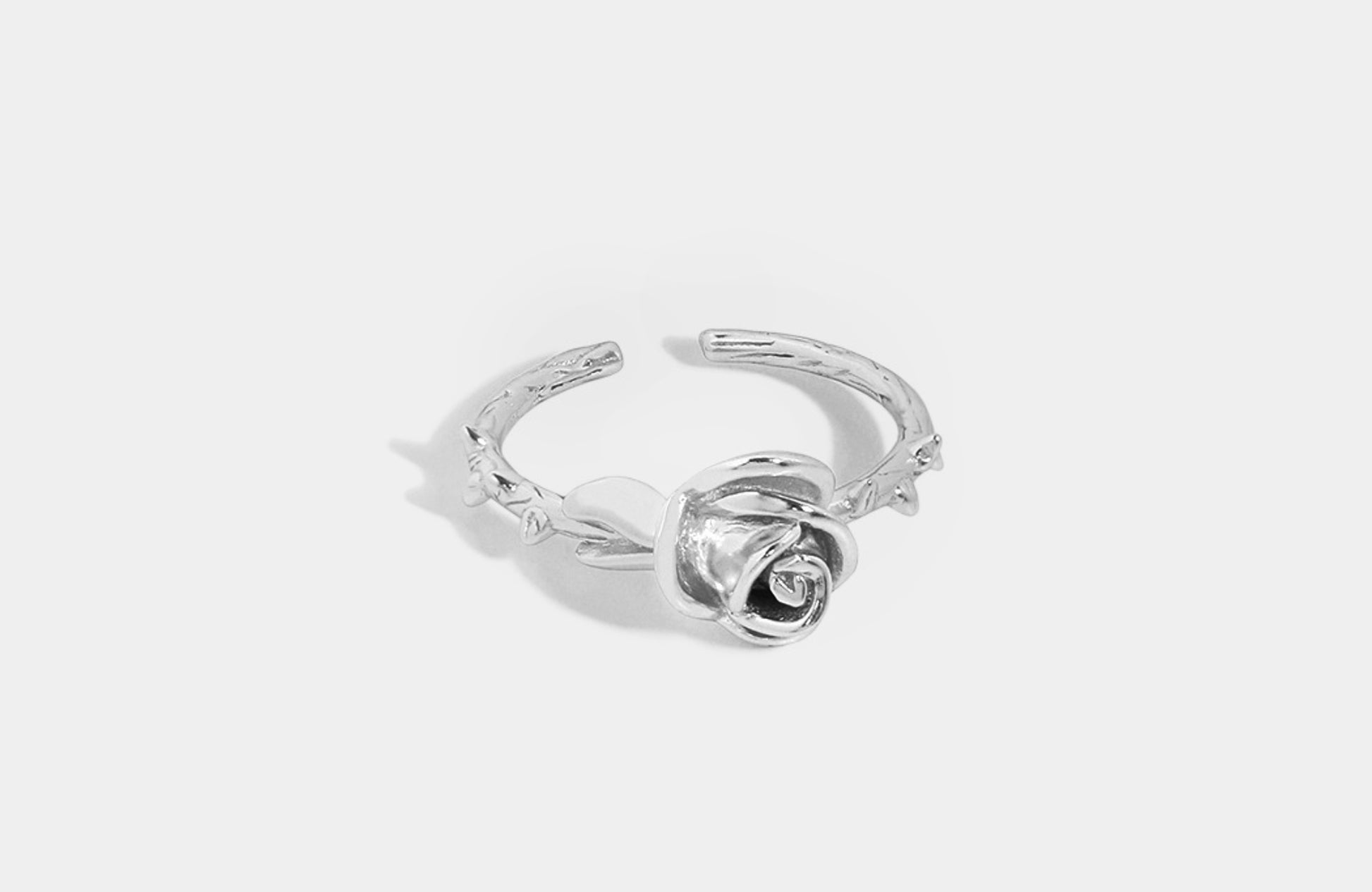 Silver rose-shaped ring on a light gray background
