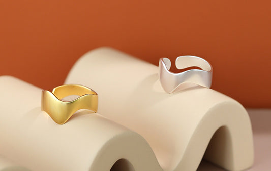Gold and silver rings on a textured beige surface with a warm brown background