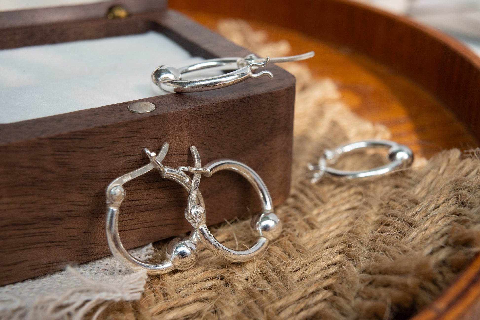 Silver hoop earrings on a wooden box with burlap fabric