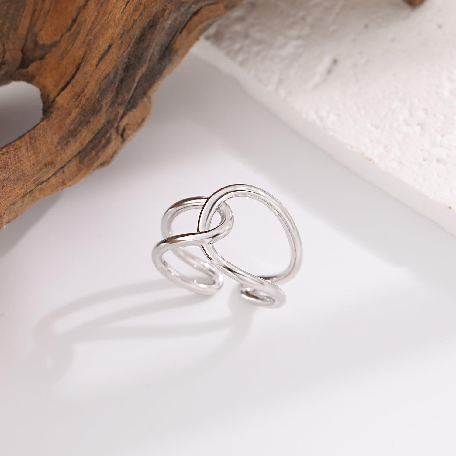 Silver ring with a unique design on a white surface with wooden and stone elements.