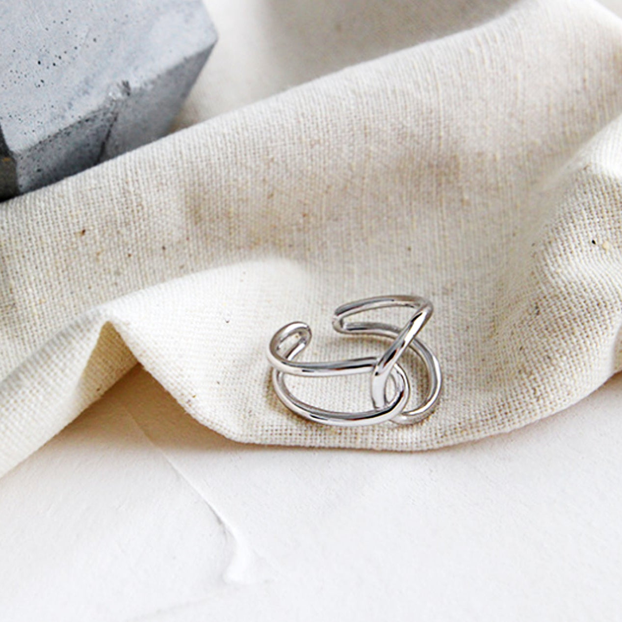 Silver ring with a unique design on a beige fabric background