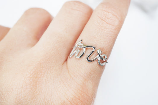 Silver ring with a unique design on a finger against a white background