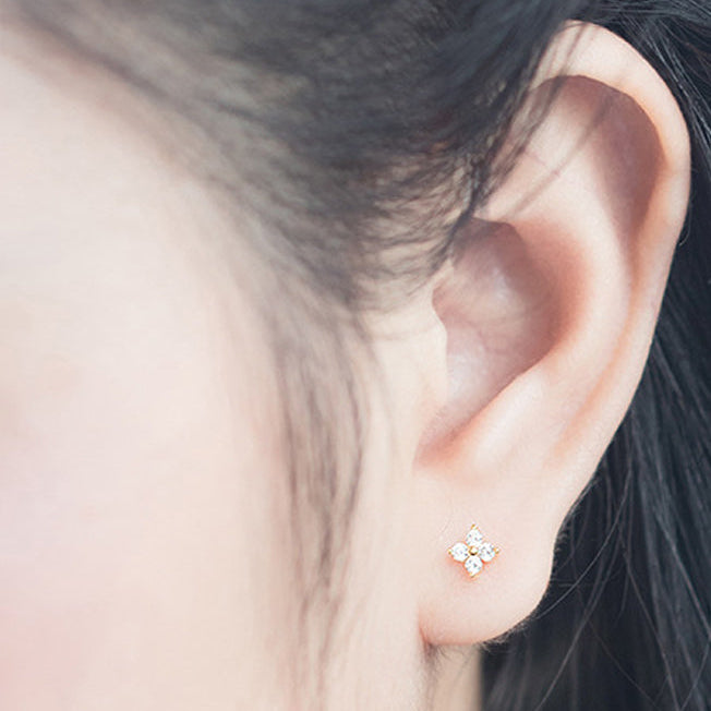 Close-up of an ear wearing a star-shaped earring with additional earrings on a light blue background.
