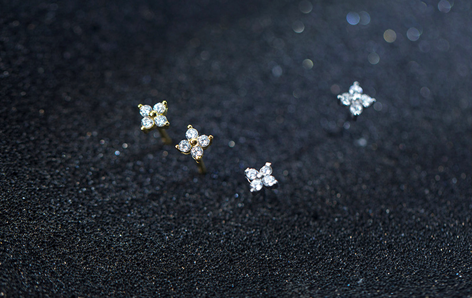 Pair of diamond stud earrings on a dark textured surface