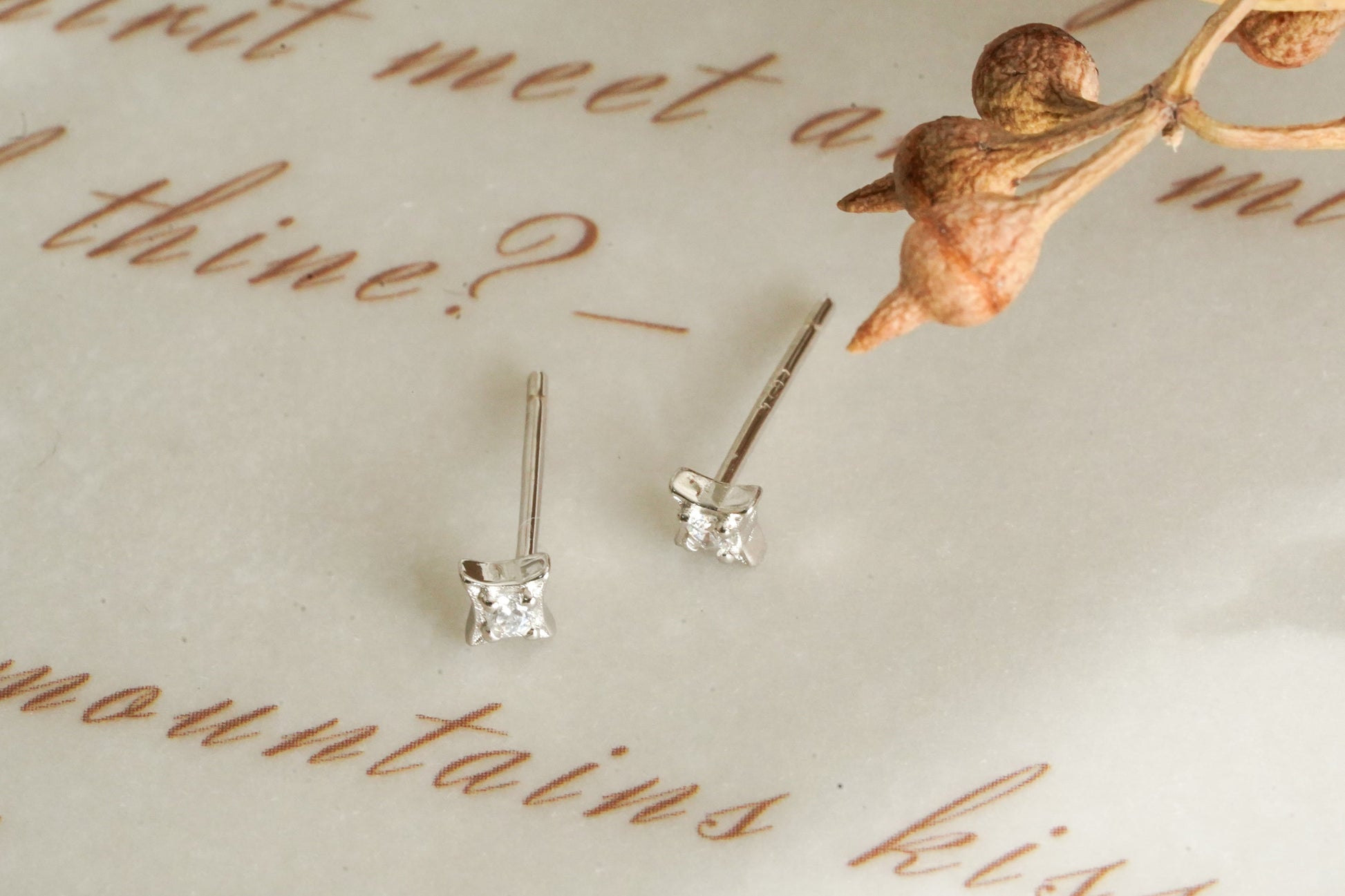 Diamond stud earrings on a piece of paper with decorative text