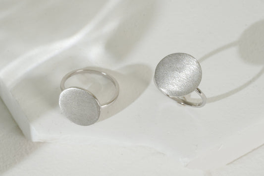 Two silver rings on a white fabric background