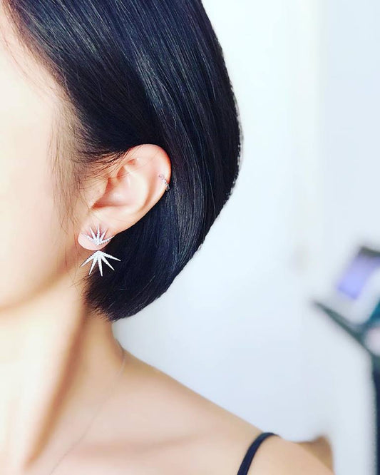 Close-up of an ear wearing a delicate earring with a blurred background