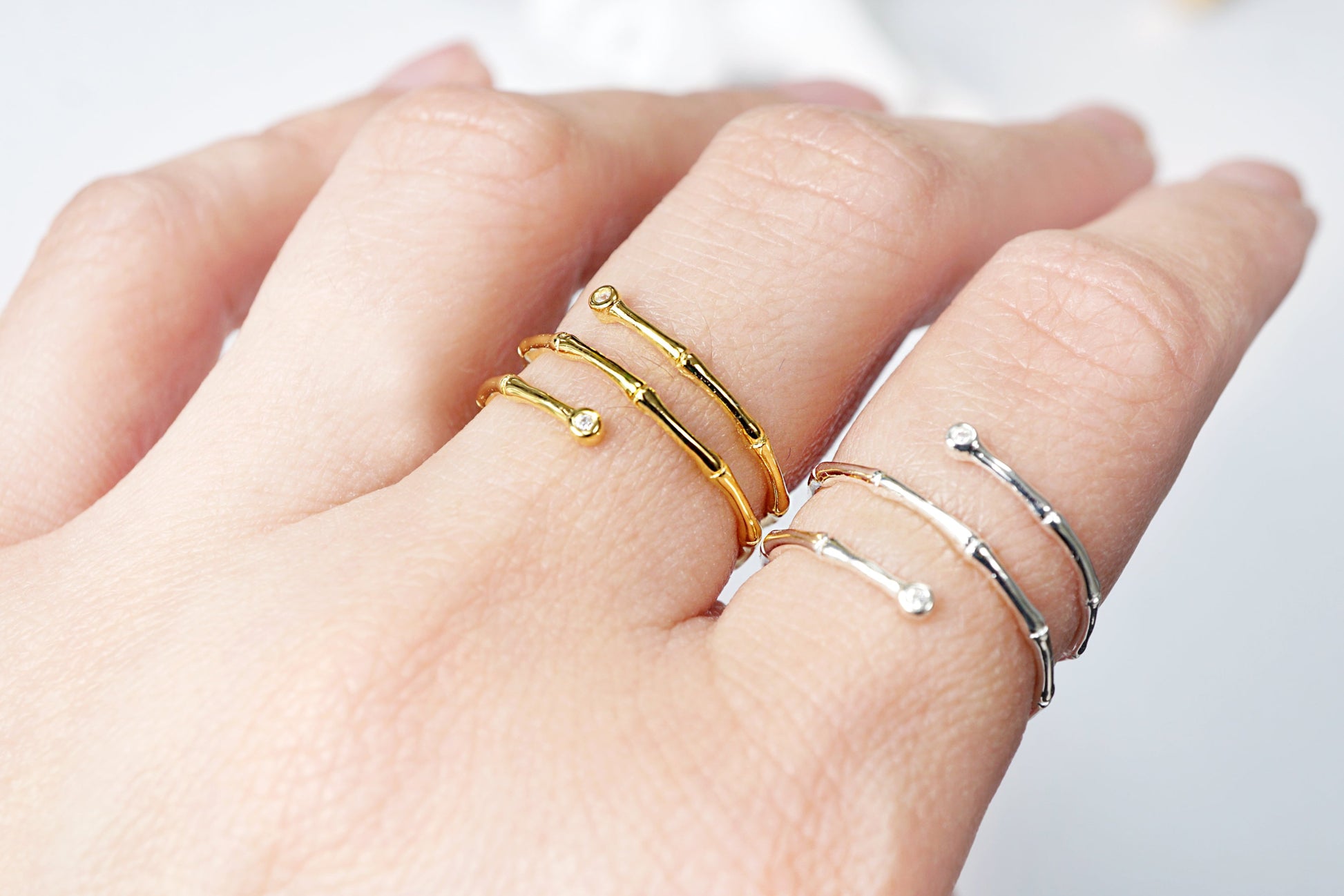 Hand wearing gold and silver rings on a blurred background