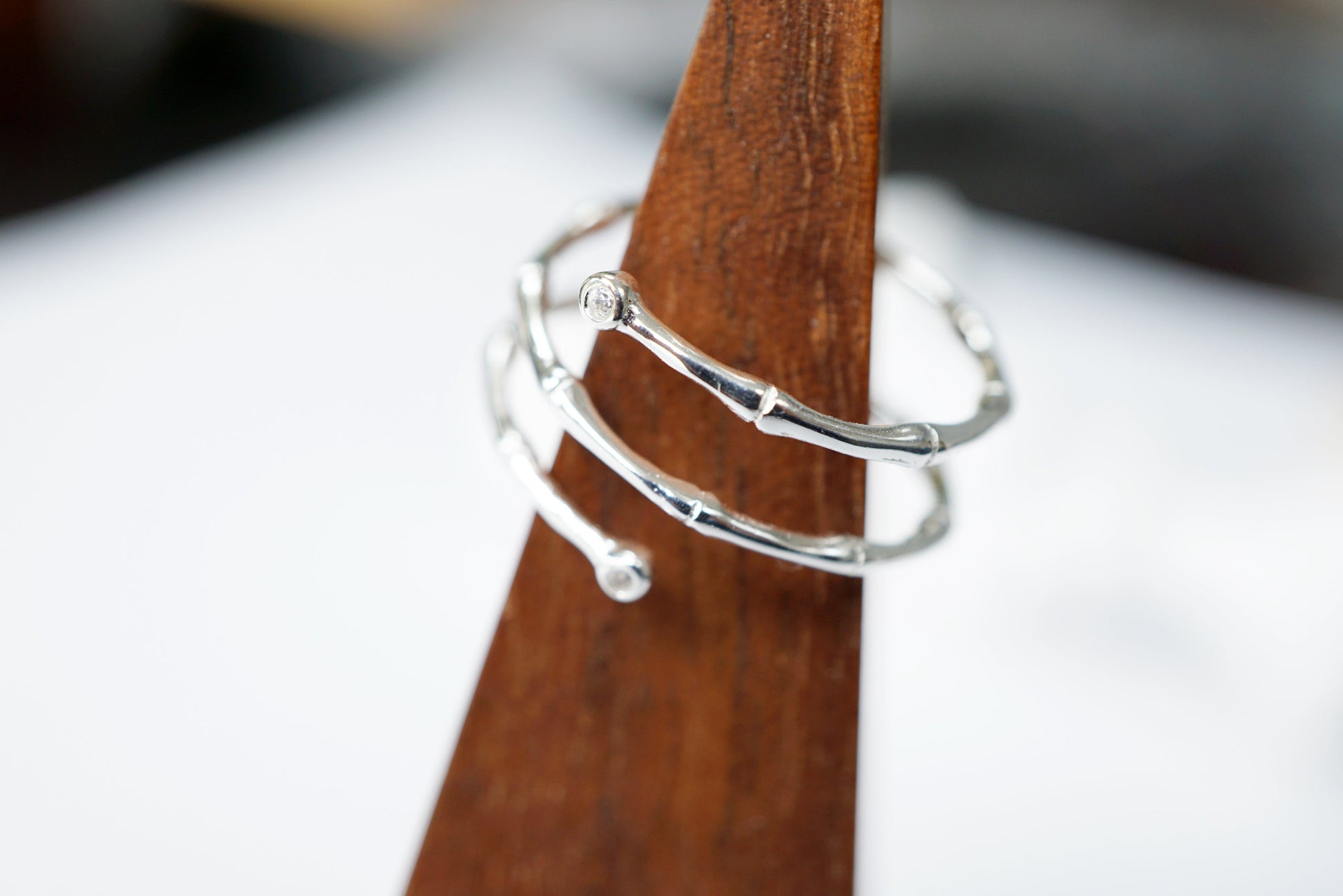 Silver ring on a wooden stand with a blurred background