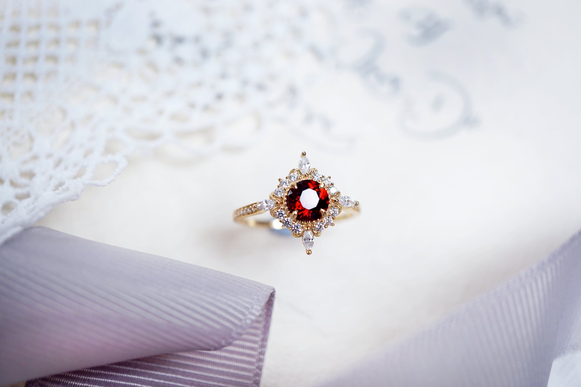 Gold ring with a red gemstone on a textured white fabric background
